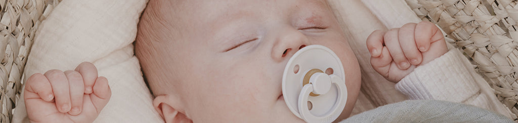 A peaceful baby sleeping soundly with a pacifier in its mouth.